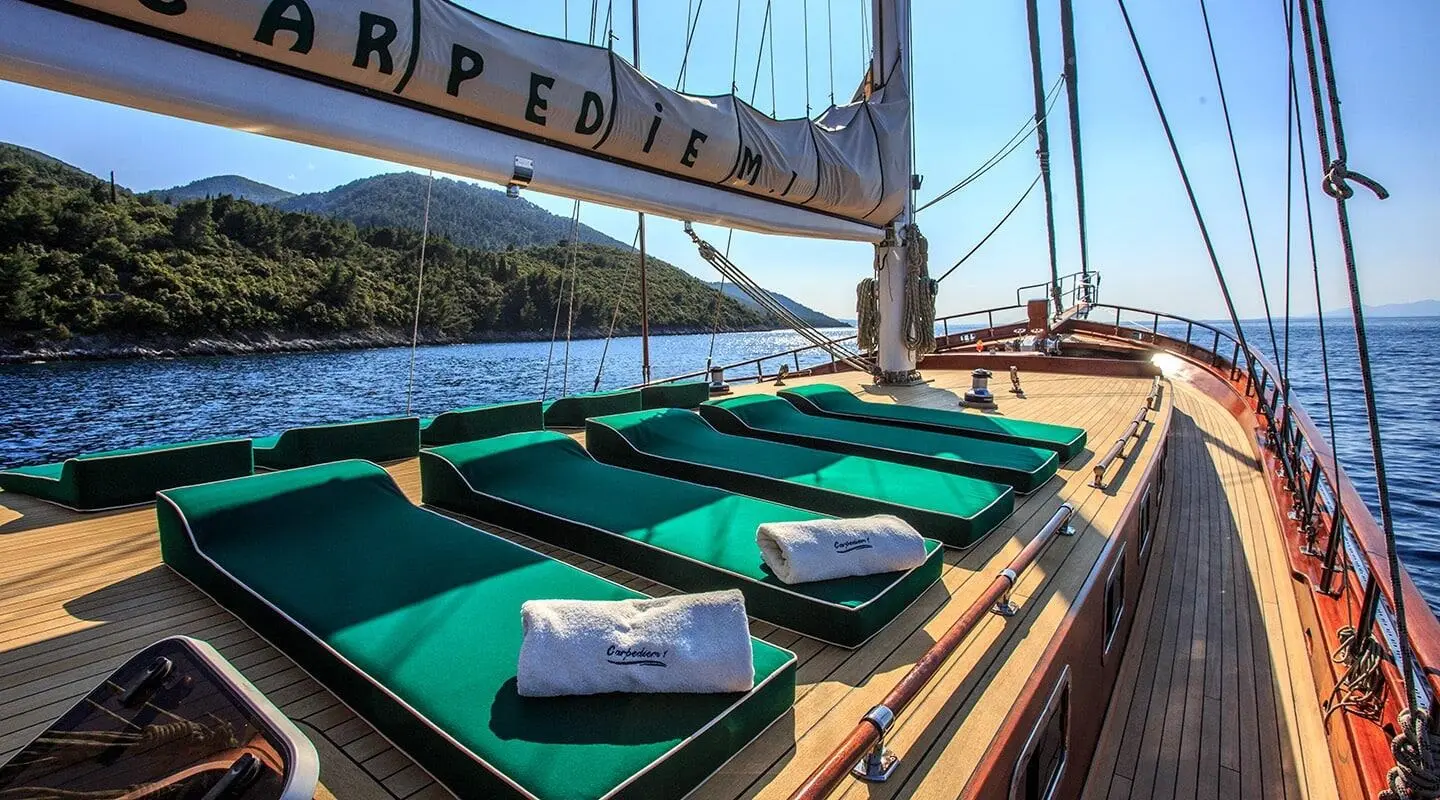 Carpe Diem 7 luxury yacht deck with green sunbeds and sails at sunset