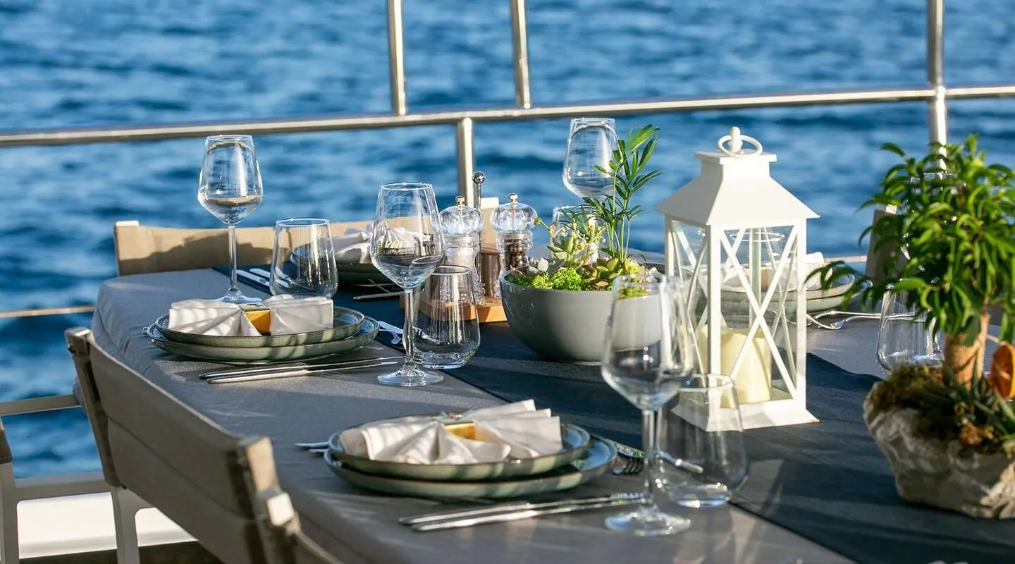 Good Life yacht at sunset with dining setup on deck, blue sea backdrop