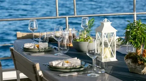 Good Life yacht at sunset with dining setup on deck, blue sea backdrop