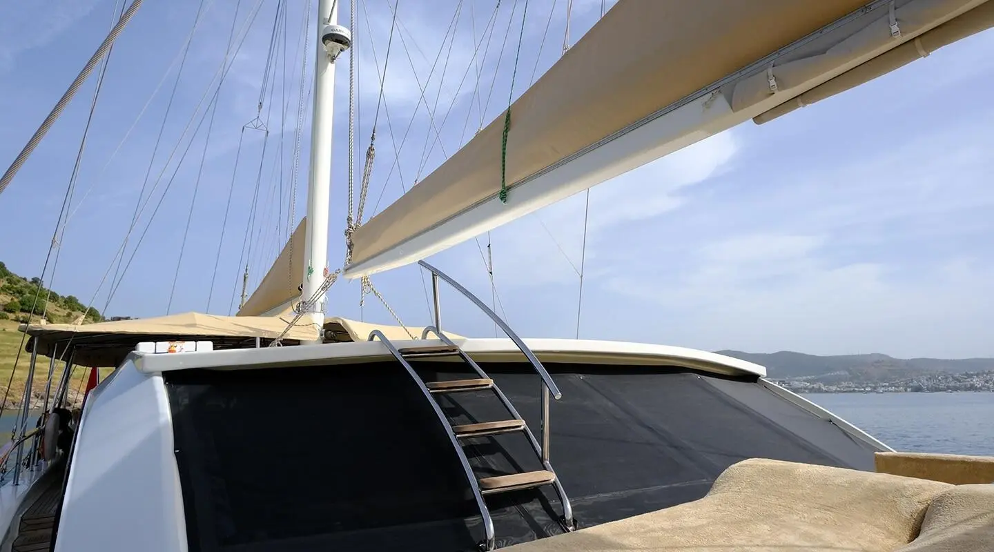 Queen Of Sea yacht deck with sails unfurled, calm blue sky at sunset