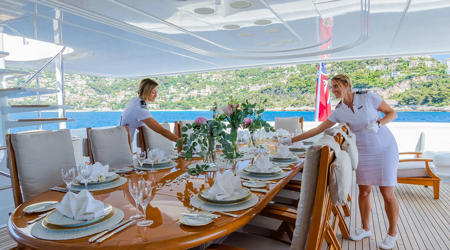Crew dining on a yacht deck with table settings under a canopy aboard Apogee