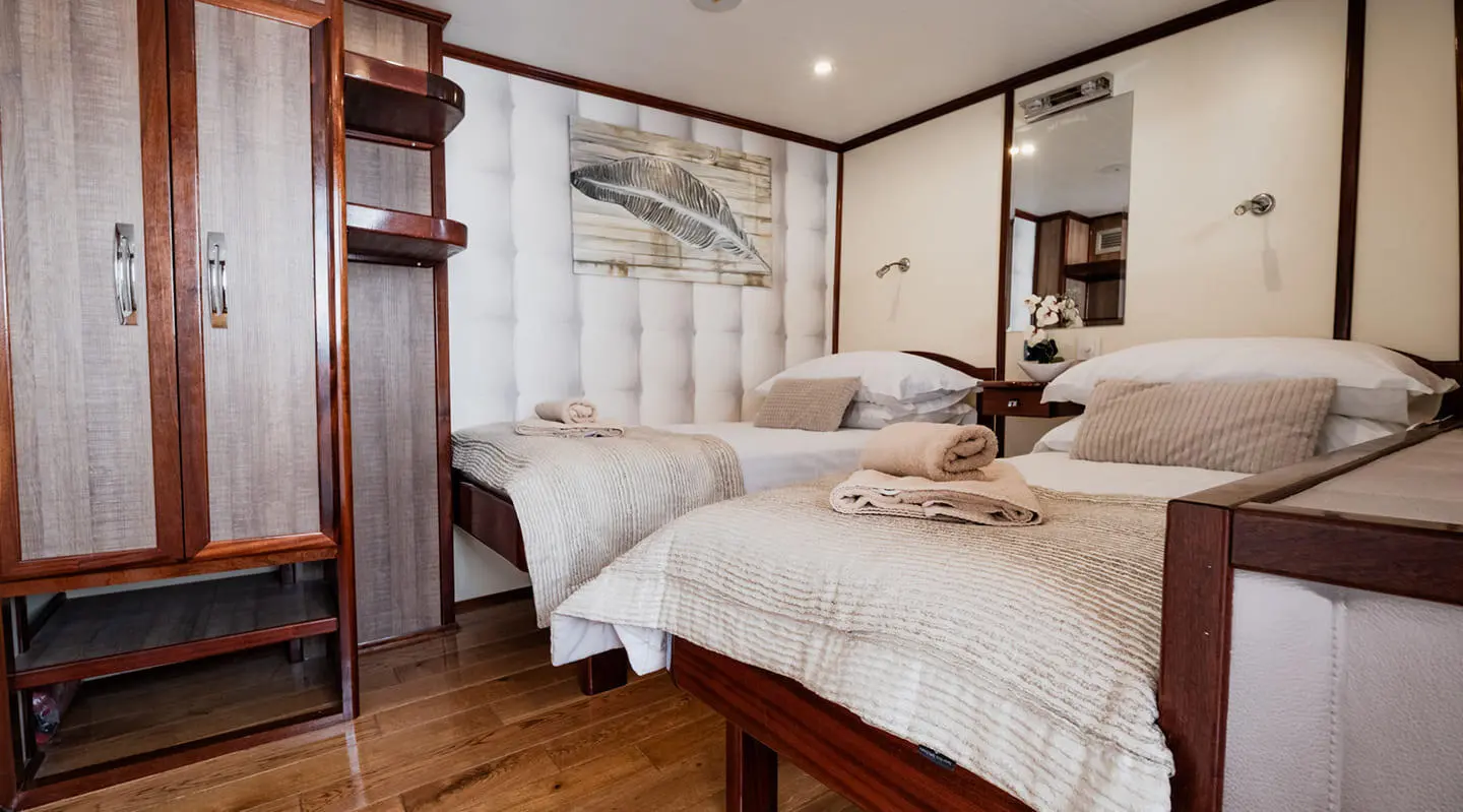 Gulet Mendula twin cabin interior with two beds, wood accents, and soft lighting