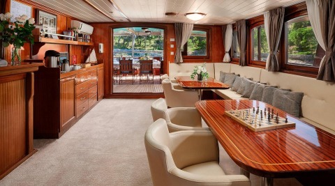 Luna yacht interior: wood-paneled salon with dining area and chessboard on glossy table
