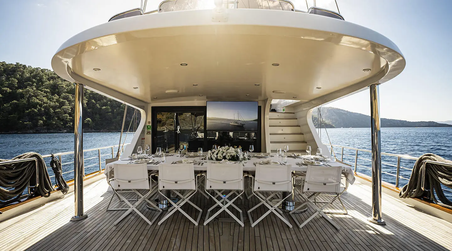 Queen Of Makri yacht exterior deck with dining chairs at sunset