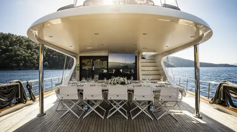 Queen Of Makri yacht exterior deck with dining chairs at sunset