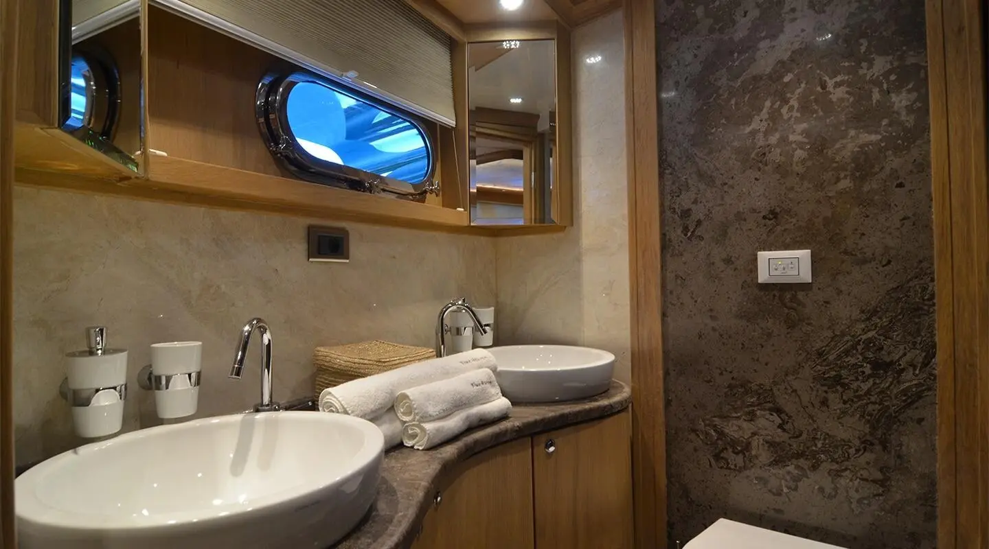 Small bathroom aboard Blue Heaven gulet with double sinks and wooden cabinetry