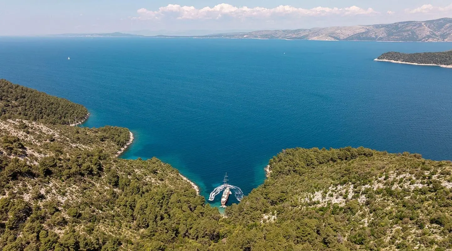 Dalmatino yacht anchored on rocky coastline overlooking deep blue sea