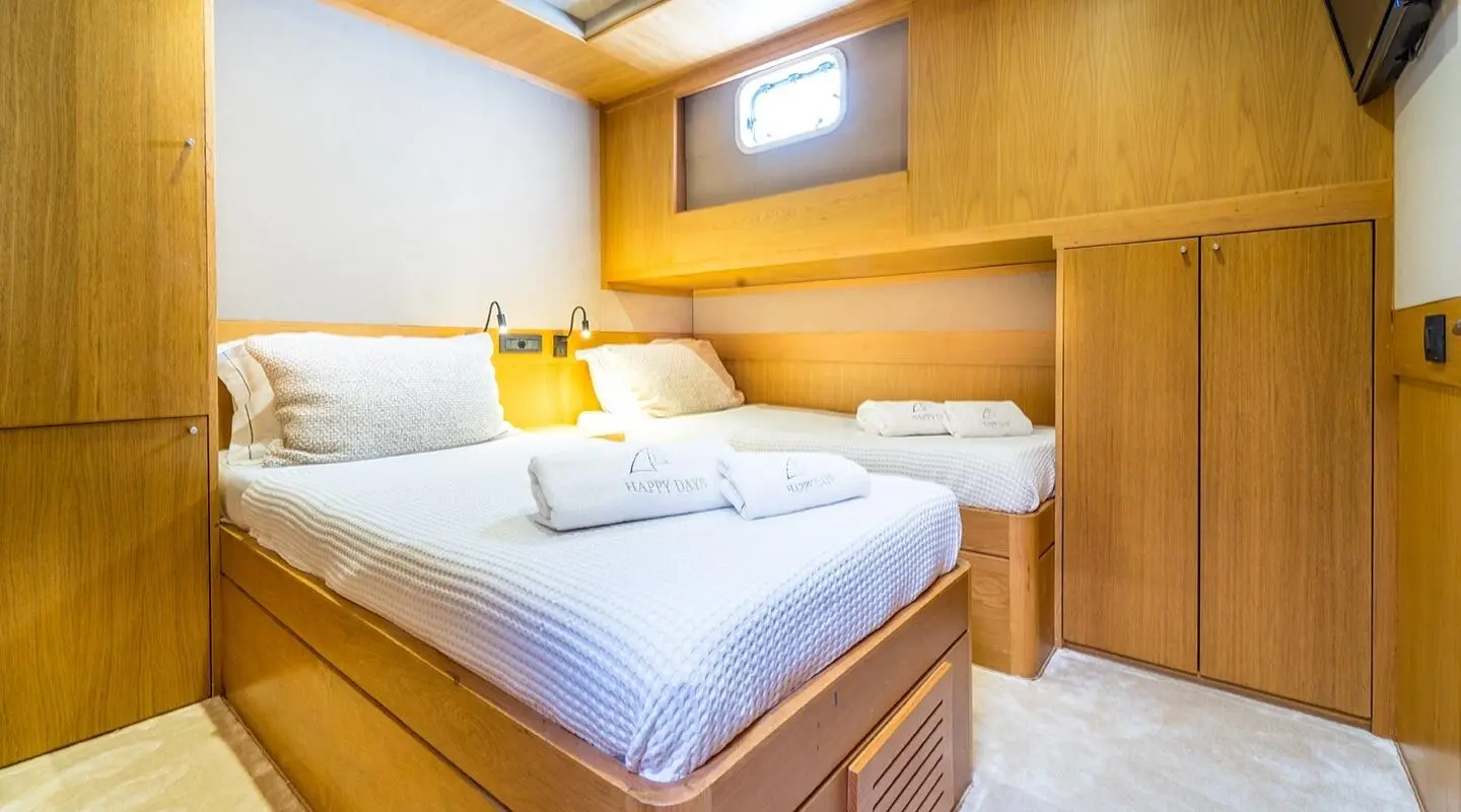 Wood-paneled cabin with two beds and built-in storage in a yacht interior