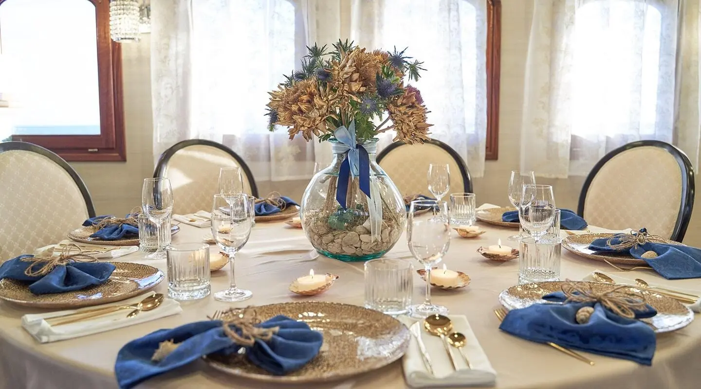 Casablanca yacht dining table set with flowers and blue napkins at sunset