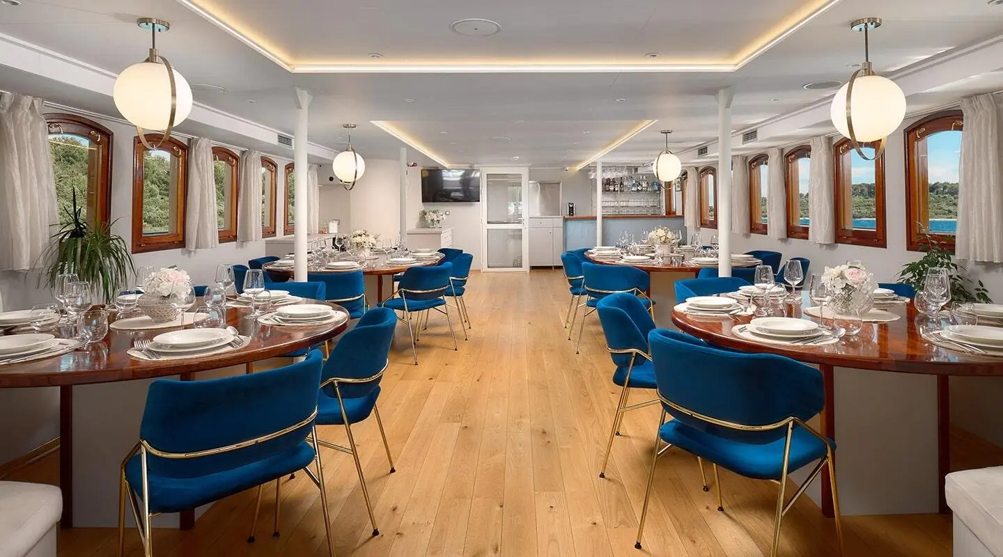 Bellezza yacht dining area on deck aboard at sunset with blue booths