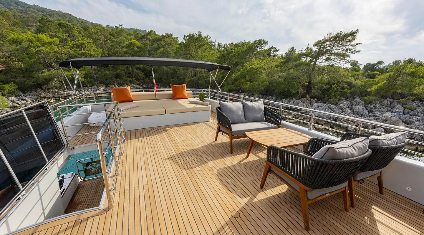 Simay M yacht deck with seating, striped railing, and trees in background