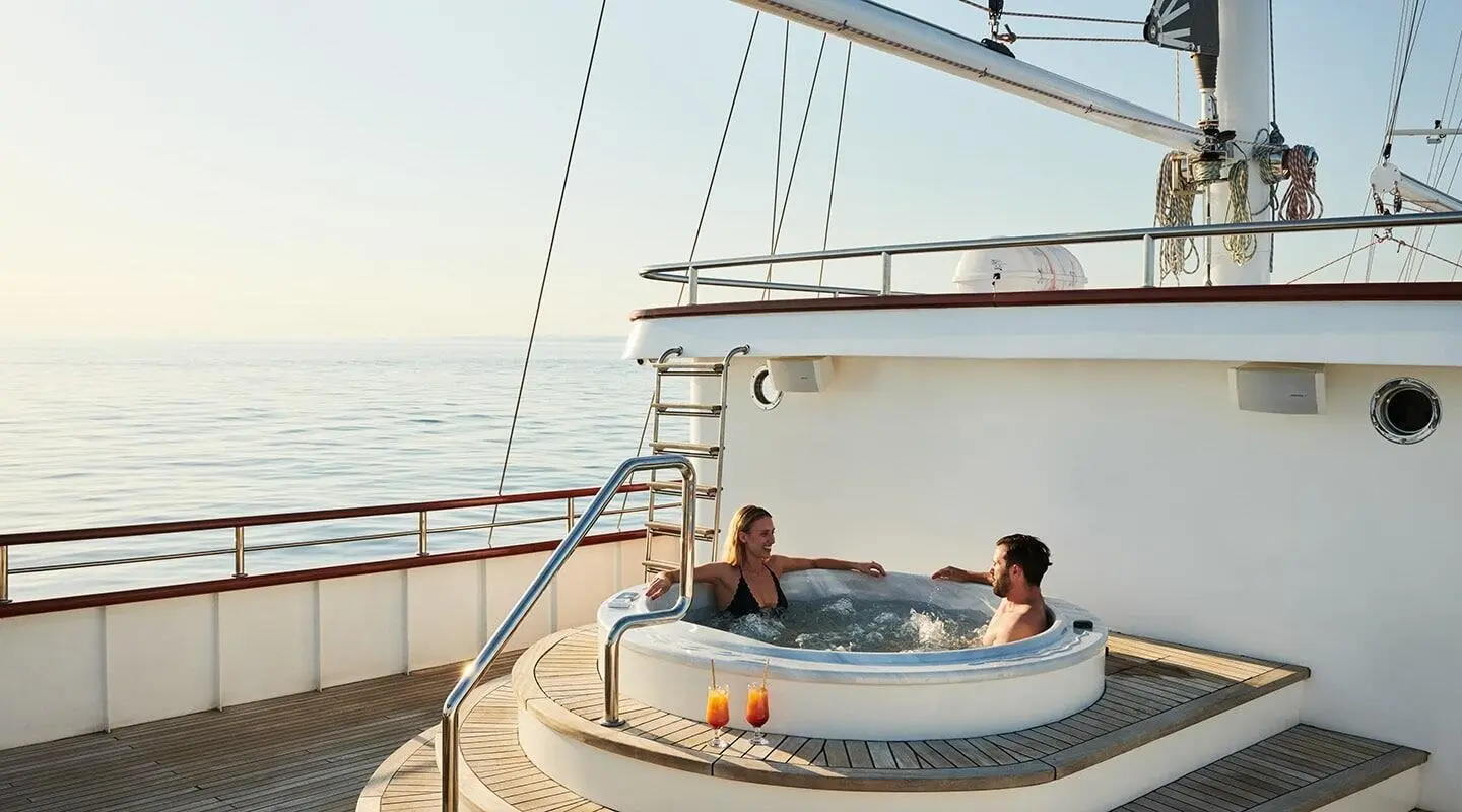 Yacht Corsario with people on a round dinghy near a luxurious deck at sunset