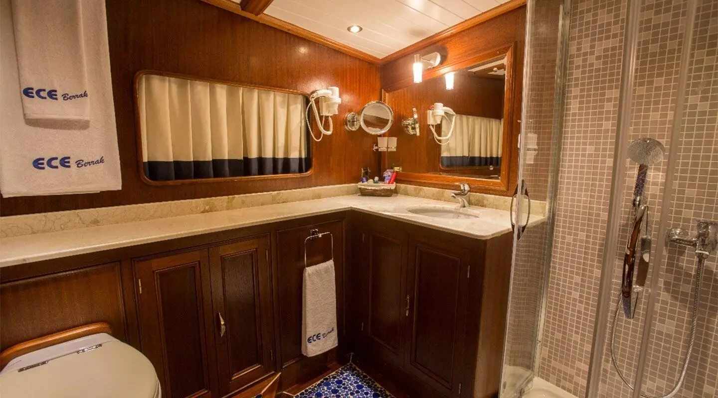 Small luxury yacht guest bathroom with vanity, mirror, and warm lighting