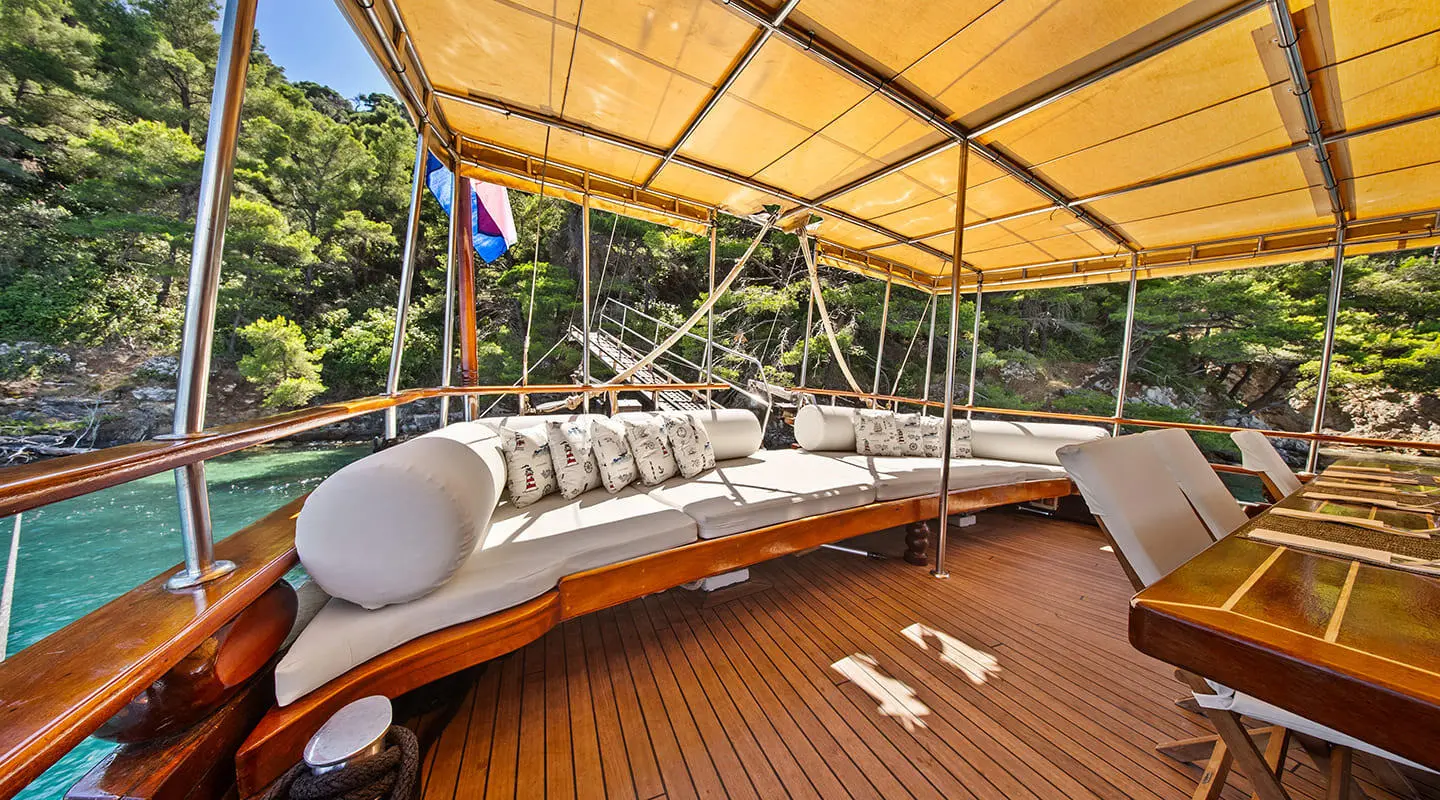 Eleganza yacht deck under tan canopy with seating and ropes, sunset glow