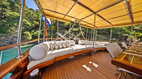 Eleganza yacht deck under tan canopy with seating and ropes, sunset glow