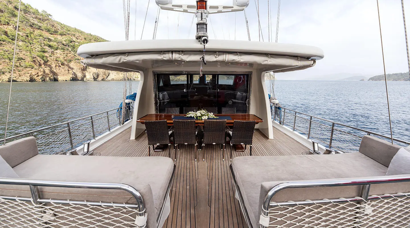 Kayhan 3 yacht deck seating area with helm, wooden flooring, and rigging at sunset