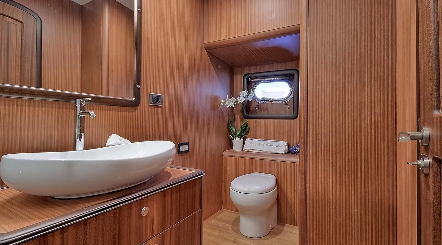Yacht bathroom on Queen Of Salmakis with wood paneling, sink, mirror, and toilet