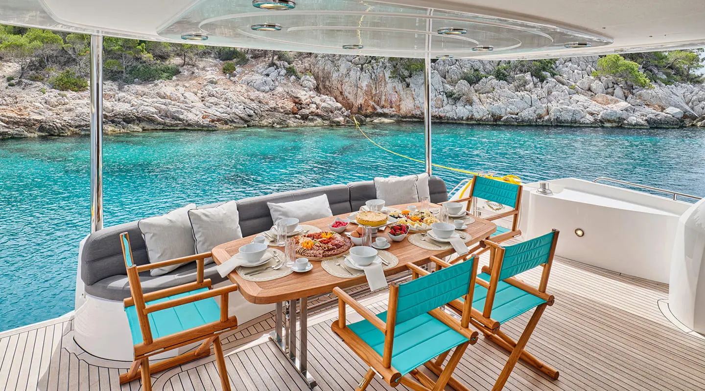 aft deck seating on M Five yacht with turquoise cushions and dining setup