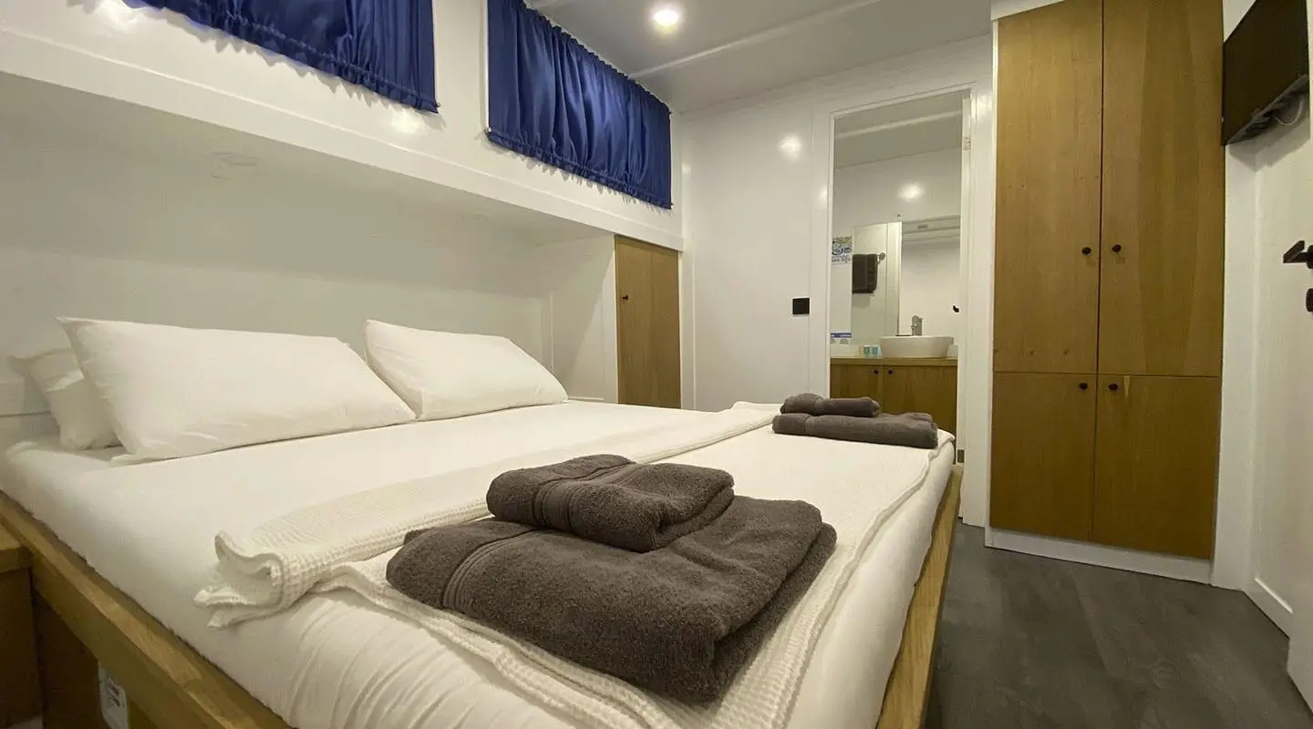 Maske 5 yacht interior: luxurious cabin with large bed, brown throws, soft lighting