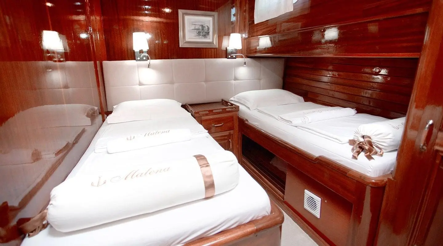 Interior of Malena gulet showing twin cabins with white bedding and polished wood panels