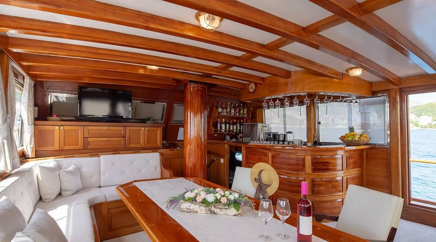 Andi Star yacht interior with wooden beams, dining table set, and window view