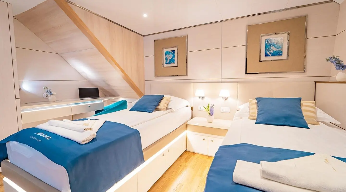 Interior of a Riva motor yacht with twin cabins, wood steps, and blue bedding