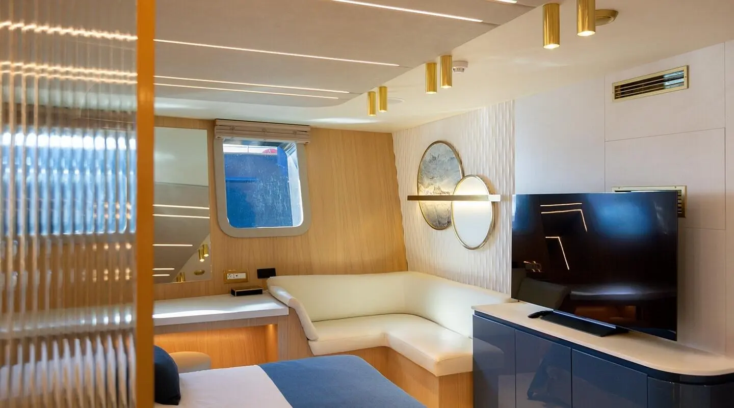 Luxurious yacht interior with a white seating area and TV mounted on blue cabinets