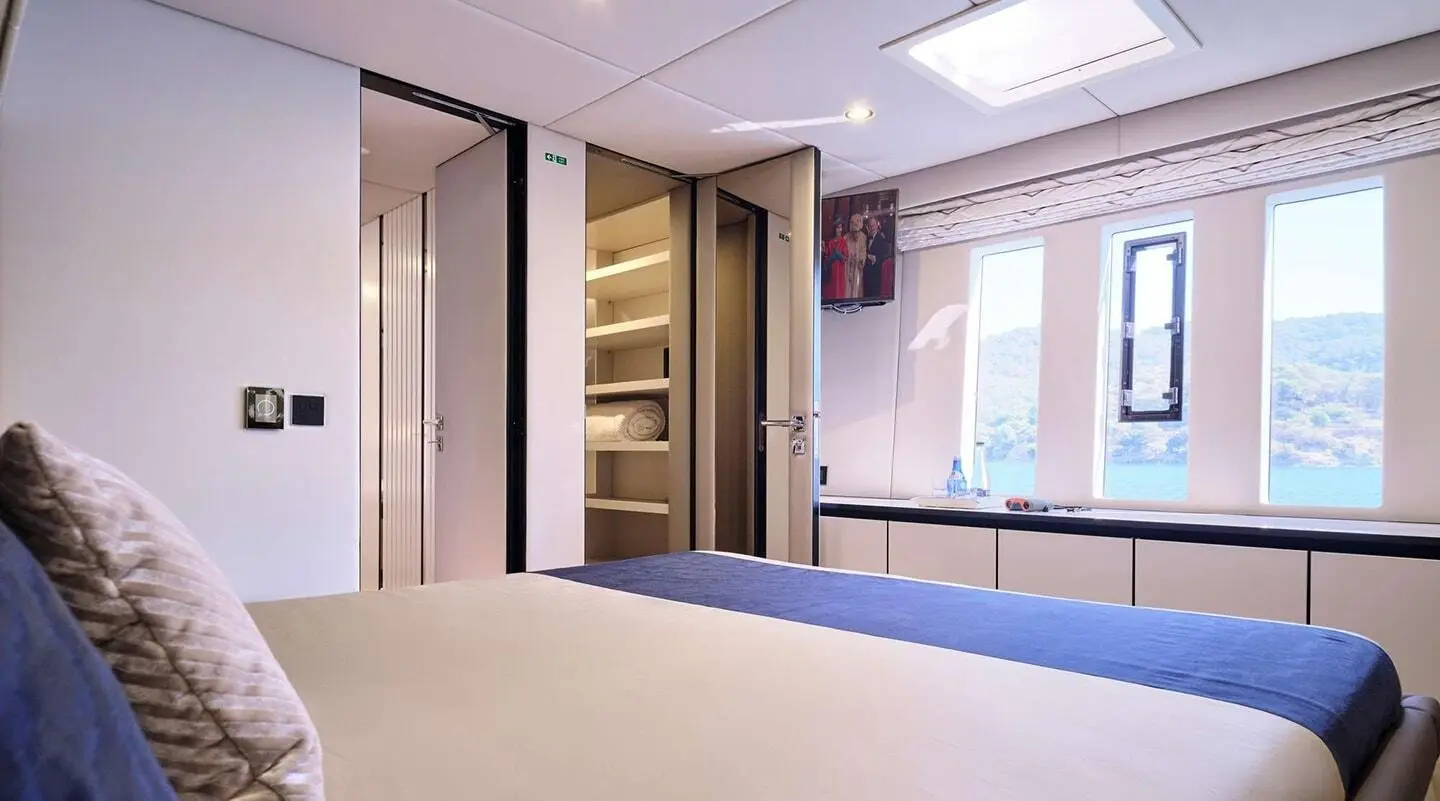 Interior of a cabin with open wardrobe, bed and windows showing outside view