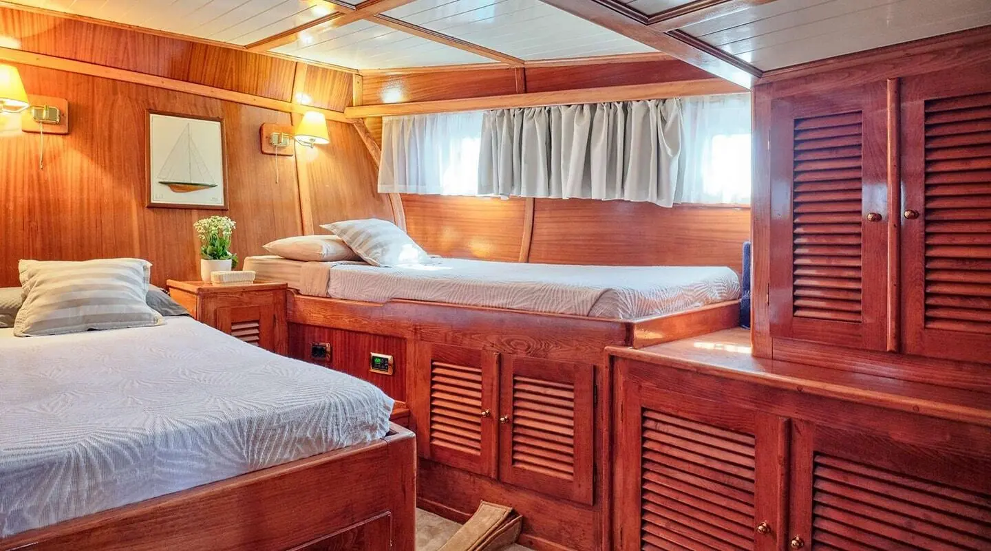 Interior of Myra gulet with twin cabin beds, wooden cabinetry, and porthole light