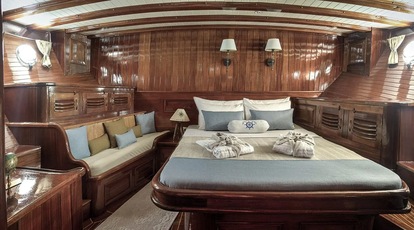 Master cabin on Entre Cielos gulet with bed, wood panels, and blue cushions