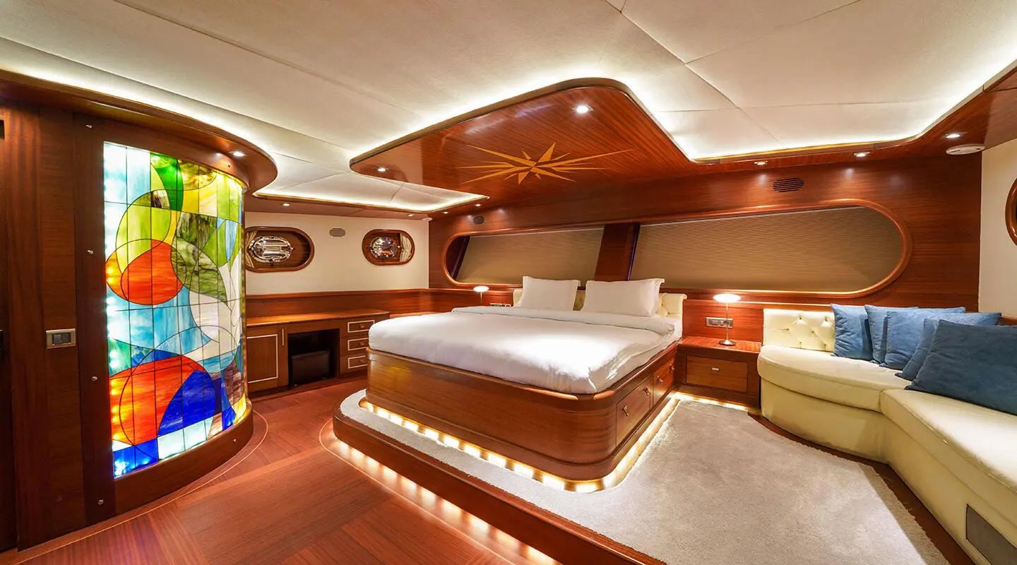 La Bella Vita yacht interior with wooden deck, bed, and warm lighting at dusk