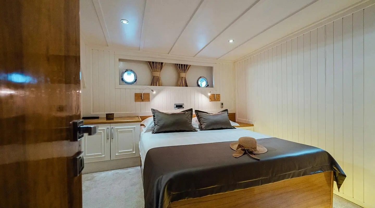 Maske yacht cabin: double bed, wood accents, porthole window, neutral tones