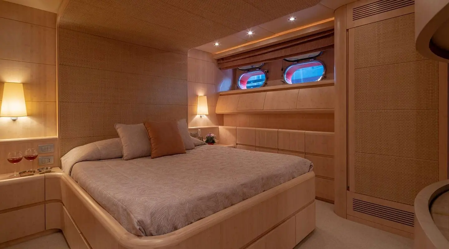 Cozy yacht cabin with double bed, warm wood paneling, and built-in storage