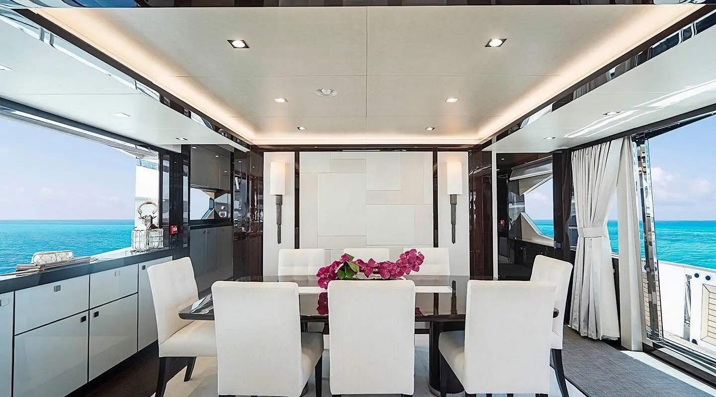 Interior dining area on Quantum yacht with large windows and a vase of flowers