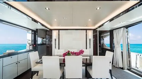 Interior dining area on Quantum yacht with large windows and a vase of flowers
