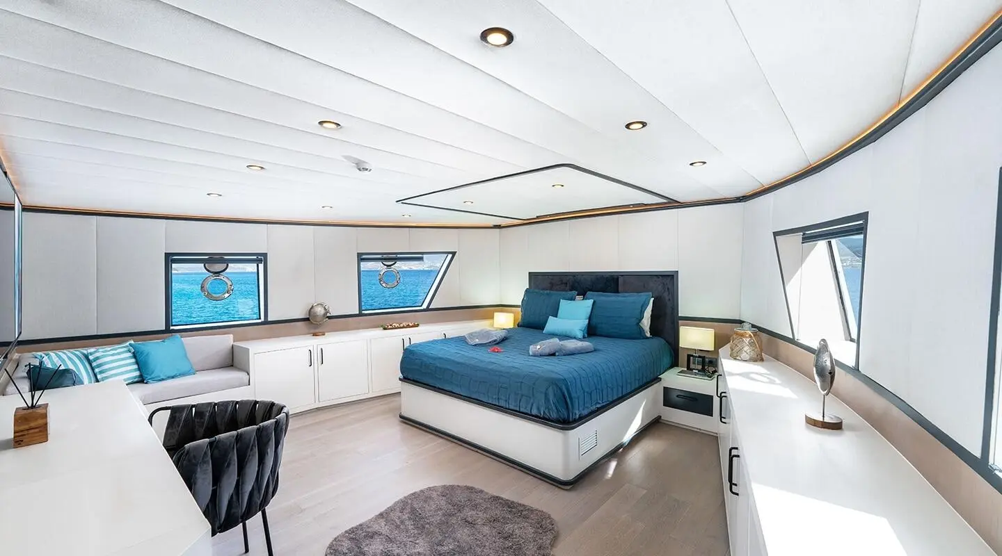 Calm Down yacht interior: bright living area with blue sofa seating and large windows