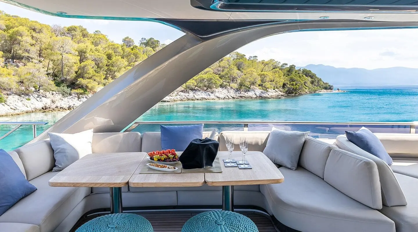 Vista yacht sundesk seating area with cushioned lounge and table on deck by blue water