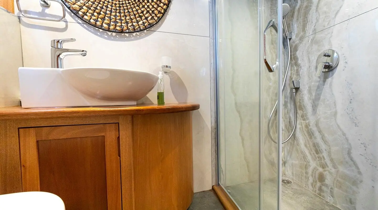 Bodrum Queen gulet bathroom with wooden cabinet and glass shower doors
