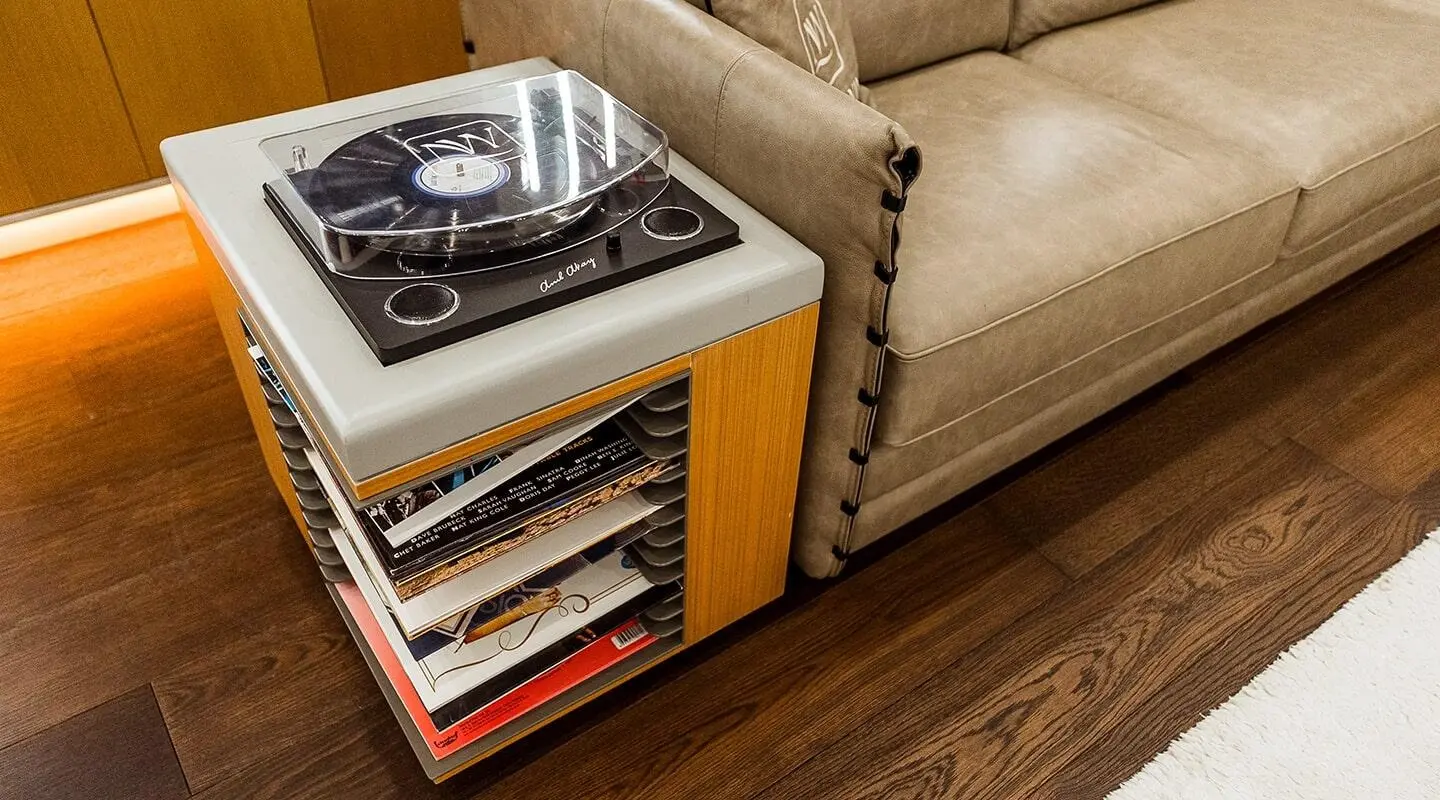 Interior yacht lounge with vinyl records storage beside beige sofa and wood floors