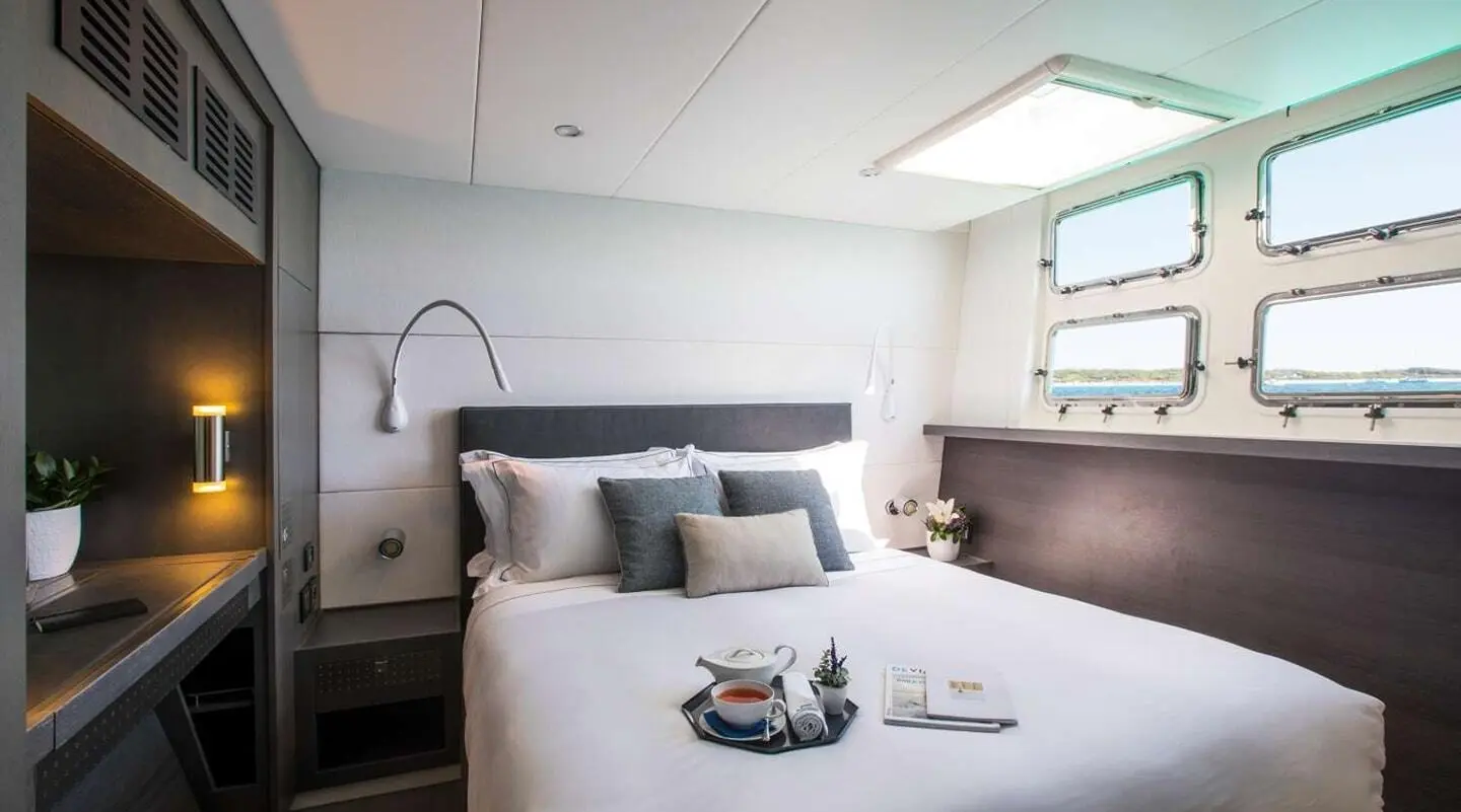 Cartouche yacht cabin interior with bed, pillows, and seating area