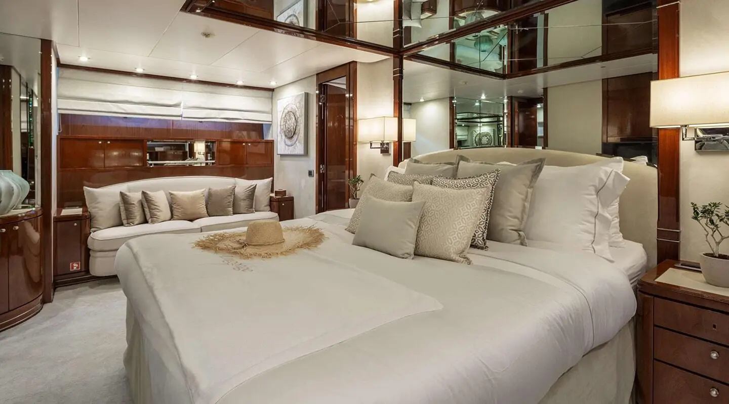 Grace yacht interior: cabin with white bedding, beige pillows, wooden accents