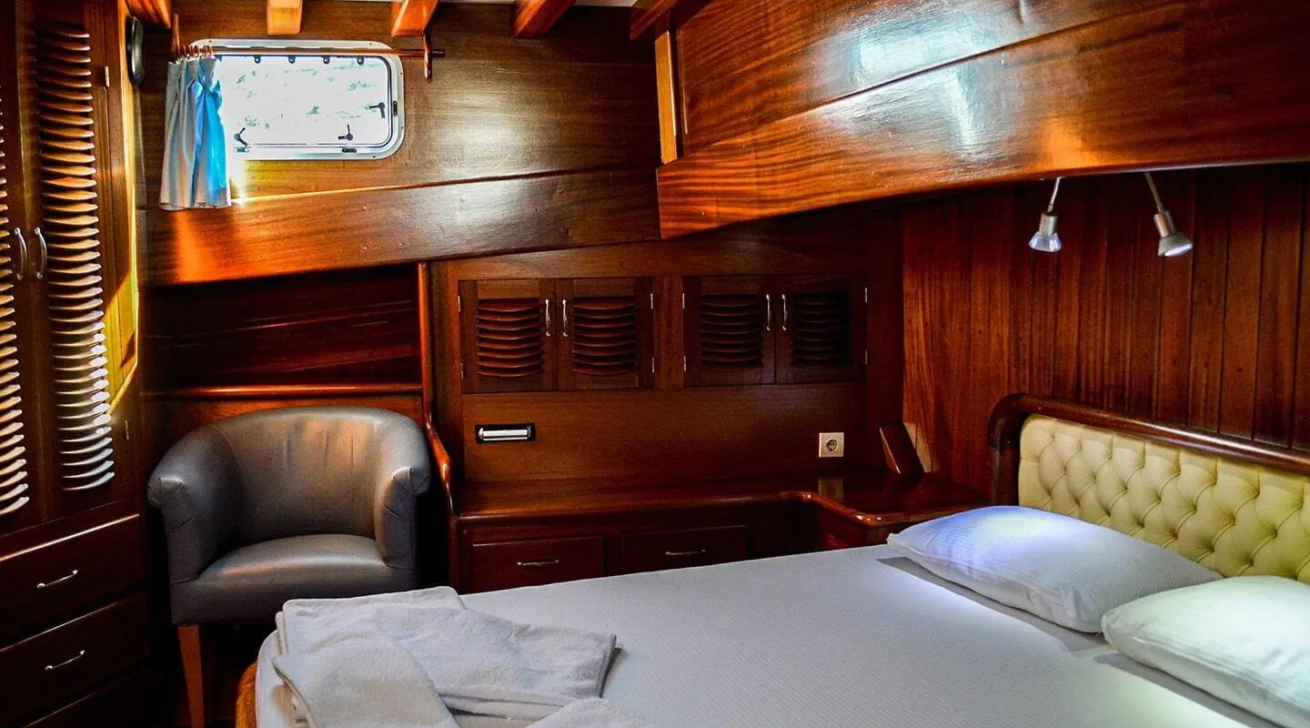 Dark wooden cabin interior with bed, bedside tables and built-in cabinets
