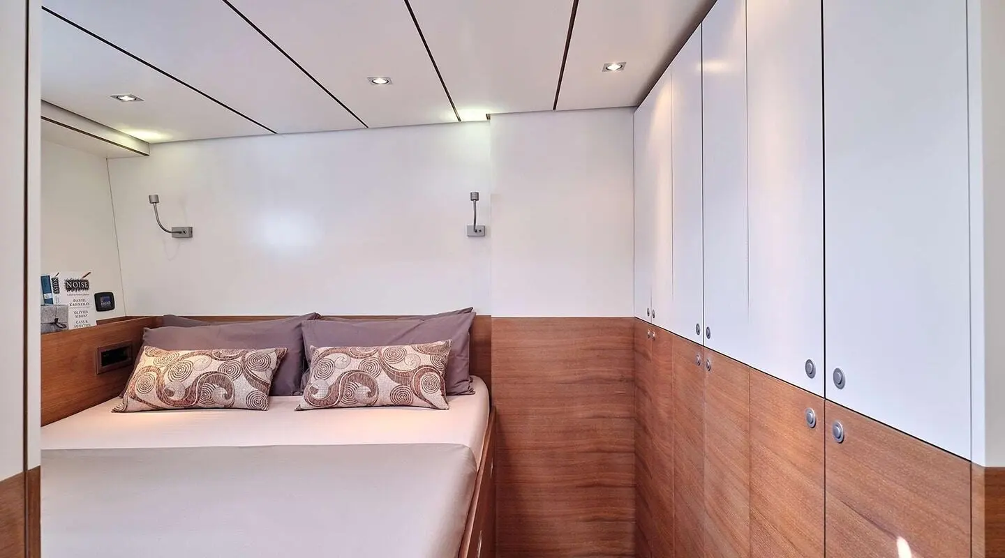 Aizu yacht deck cabin interior with white walls, brown wood paneling, and bed with cushions