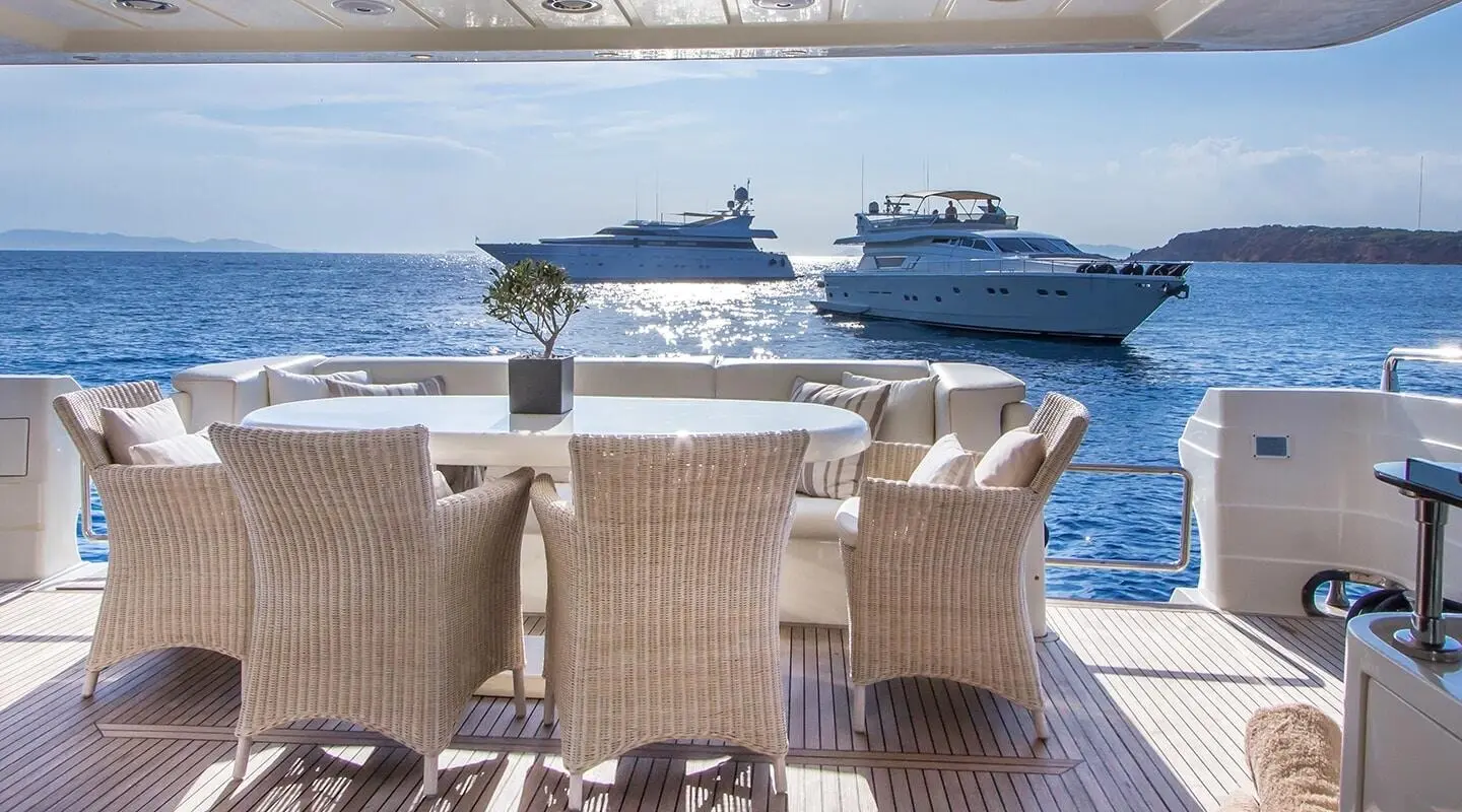 Amoraki yacht with dining chairs on deck overlooking calm blue sea at sunset