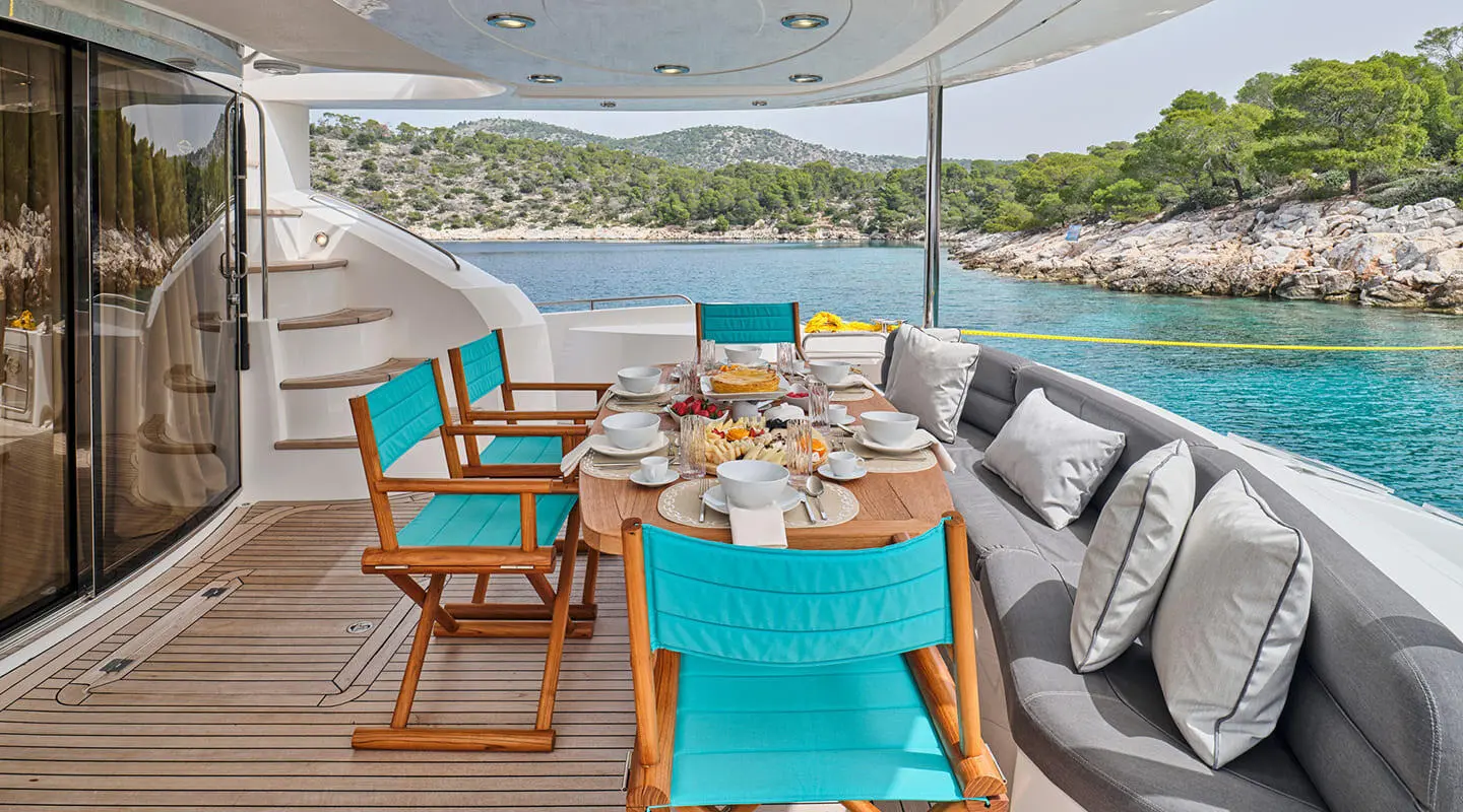 Aboard M Five yacht aft deck with turquoise chairs and a table setup