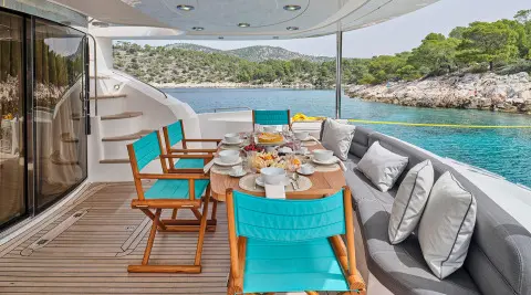 Aboard M Five yacht aft deck with turquoise chairs and a table setup