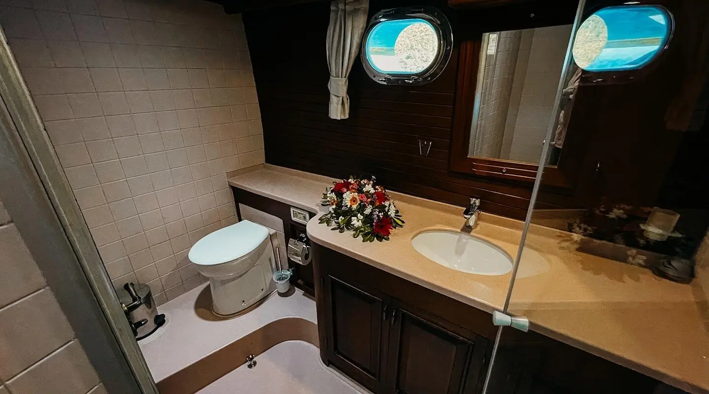 Interior of a luxury yacht bathroom with a sink, toilet, and flower arrangement