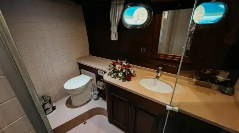 Interior of a luxury yacht bathroom with a sink, toilet, and flower arrangement