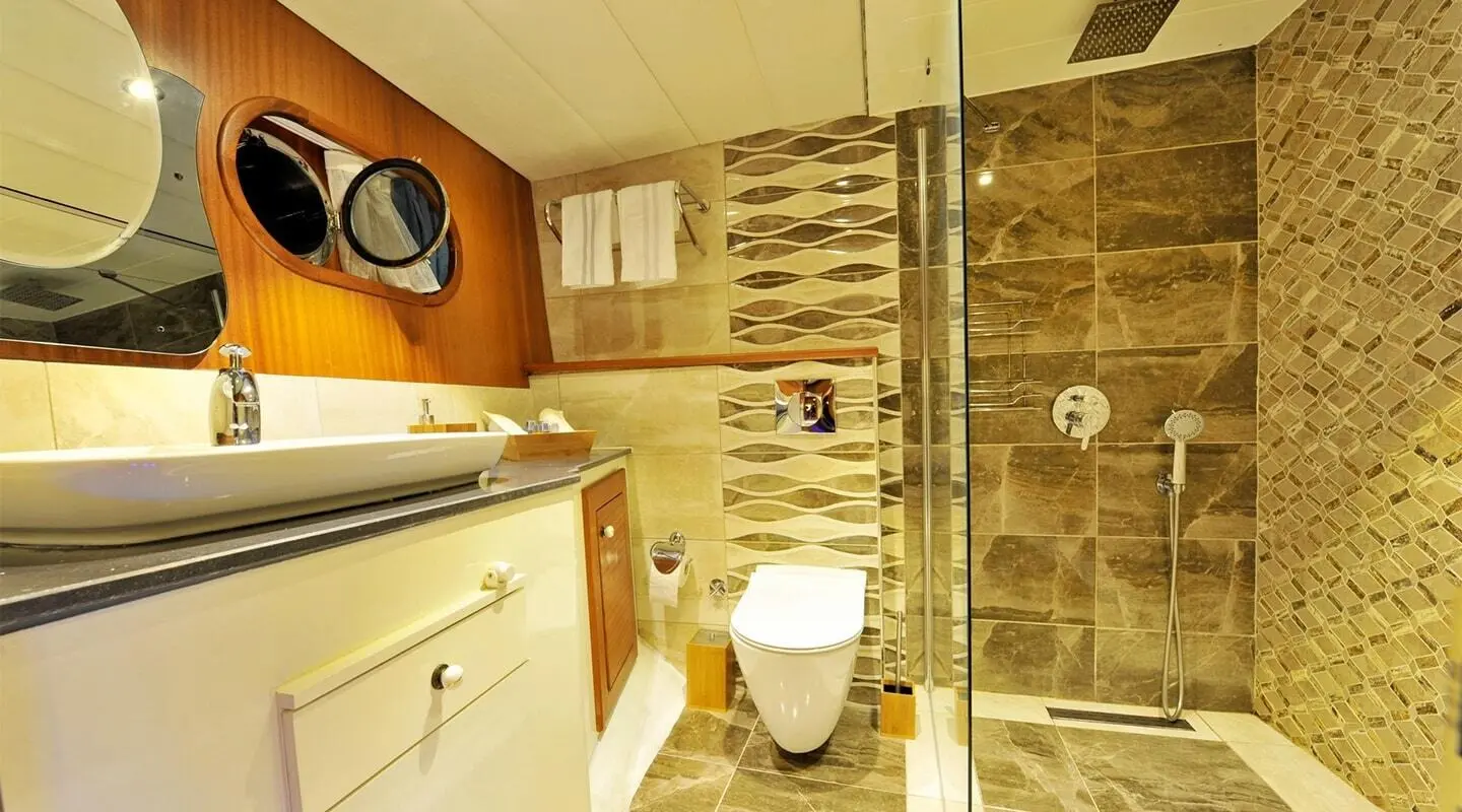 Luxurious interior shot of a yacht with polished wood, cream cabinets, and a toilet visible