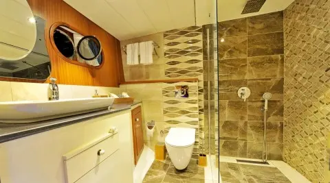 Luxurious interior shot of a yacht with polished wood, cream cabinets, and a toilet visible